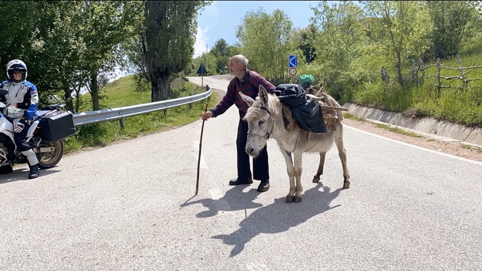 Alter Mann mit Esel segnet Motorradfahrer auf einer Motorradtour in Voskopoja, Albanien